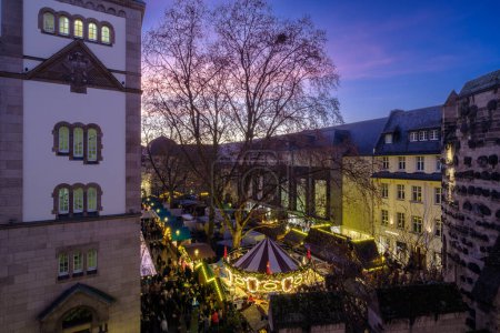 Foto de Bonn, Alemania - 23 de diciembre de 2023: Vista de un bar de Navidad iluminado y lleno de gente que vende Glhwein, el vino caliente en el mercado de Navidad en Bonn Alemania - Imagen libre de derechos