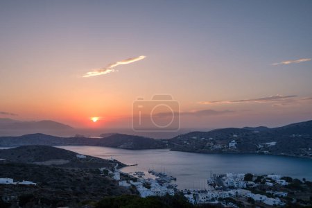 Blick auf den malerisch beleuchteten Hafen von Ios in Griechenland, während die Sonne auf dramatische Weise untergeht