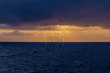 Vista panorámica del mar Egeo nublado y un amanecer dorado