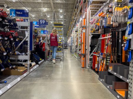 Photo for Everett, WA USA - circa September 2022: Wide view of a Lowes employee moving a stair ladder around inside the home improvement store. - Royalty Free Image