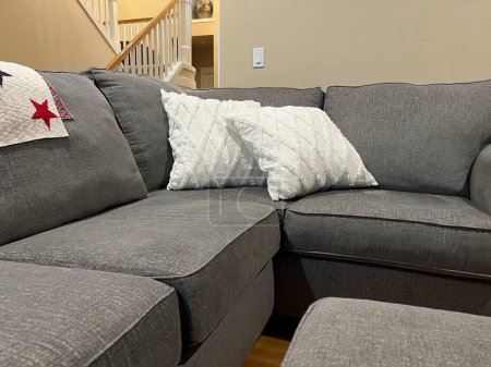 Photo for Close up, selective focus on an L shaped gray couch with white pillows and a star covered blanket in a bright living room - Royalty Free Image