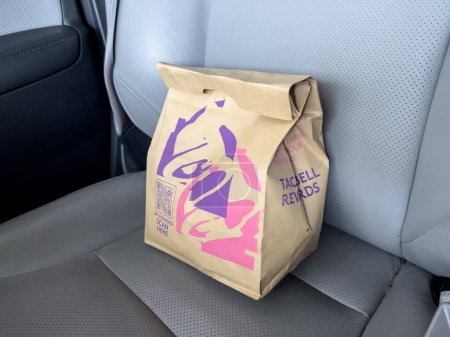 Photo for Seattle, WA USA - circa March 2023: Close up view of a Taco Bell fast food bag inside of a car. - Royalty Free Image