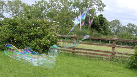 Foto de Burbuja de jabón gigante con una varita de burbuja en un jardín - Imagen libre de derechos