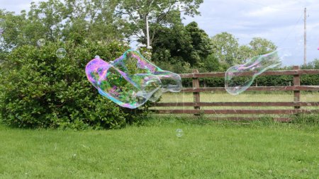 Foto de Burbuja de jabón gigante con una varita de burbuja en un jardín - Imagen libre de derechos
