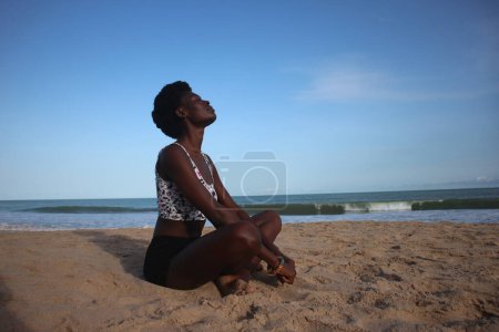 Téléchargez les photos : Sandy Asana : Pose de yoga côté plage d'une femme africaine - en image libre de droit