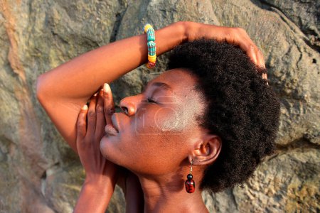 Selbstbewusst balanciert verkörpert der Kopfschuss einer Afrikanerin Ermächtigung vor Felsbrocken-Hintergrund