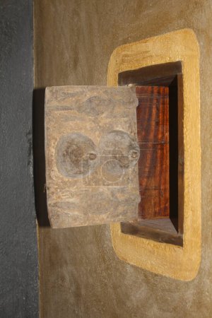 A close-up of an intricately carved wooden sculpture mounted on a wall, featuring a unique design with textured patterns.