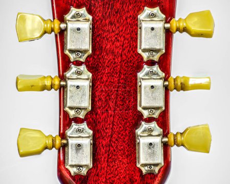 Photo for Closeup of guitar tuner or tuning pegs on red headstock.  Classic old school vintage kluson deluxe double ring circa 1966 on cherry color Gibson SG solid guitar standard, electric musical instrument - Royalty Free Image