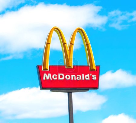 Foto de OCALA, FLORIDA USA - 14 DE OCTUBRE DE 2023 McDonalds logo blue sky background with white clouds. Signo icónico de arco dorado amarillo alto visto desde la concurrida carretera o interestatal, la cadena de comida rápida más famosa del mundo - Imagen libre de derechos