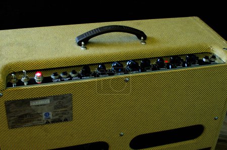 Photo for Old vintage retro style guitar tube amp or amplifier yellow tweed design Isolated on dark background. Control Volume , treble, bass, tone buttons and knobs as seen from back view Oct 14, 2023 Florida - Royalty Free Image