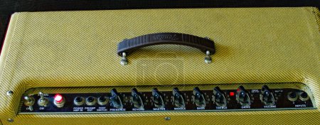 Photo for Old vintage retro style guitar tube amp or amplifier yellow tweed design Isolated on dark background. Control panel Volume , treble, bass, tone buttons and knobs Oct 14, 2023 Florida - Royalty Free Image