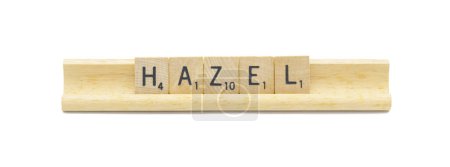 Konzept der beliebten neugeborenen Mädchen Vorname von HAZEL mit quadratischen Holzfliesen englischen Buchstaben mit natürlicher Farbe und Maserung auf einem Holzständer auf weißem Hintergrund isoliert