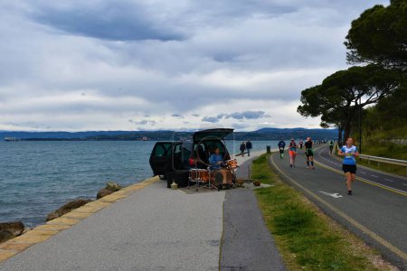 Téléchargez les photos : Izola, Slovénie - 16 avril 2023 : Homme tambour à côté d'un van sur la côte adriatique de la mer au marathon d'Istrie sur la route côtière de Kope à Izola dans la région littorale de Slovénie - en image libre de droit