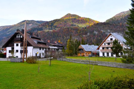 Foto de Casas en Gozd Martuljek pueblo en Gorenjska, Eslovenia con bosque de colores otoñales cubierto de montañas Karavanke - Imagen libre de derechos