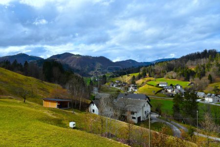 View of Poljanska dolina valley and buildings in Gorenja vas village and forest covered hill in Gorenjska, Slovenia