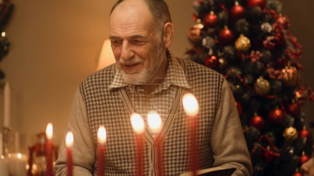 Photo for Senior man reads Bible on family Christmas dinner. Happy family praying before celebrating Christmas or New Year 2023. Served holiday table with delicious meal and candles. Winter holidays. - Royalty Free Image