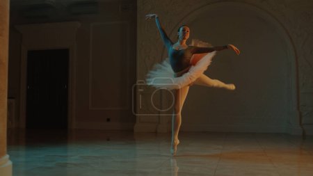 Téléchargez les photos : Cinematic shot of graceful female ballet dancer on choreography rehearsal in theater lobby, practicing elegant movements. Ballerina in tutu before performance in opera. Classical theatrical ballet art - en image libre de droit