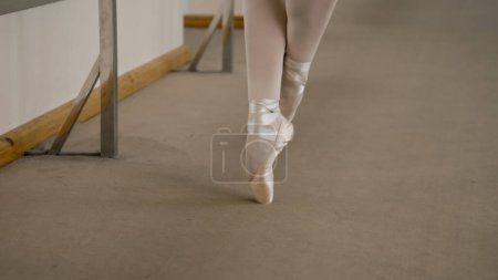 Photo for Close-up feet shooting of professional ballerina standing on tiptoe in pointe shoes at dance studio. Ballet dancer prepares for performance. Woman doing classic ballet exercises. Classic ballet school - Royalty Free Image