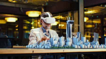 Photo for Male engineer uses VR headset and wireless controllers, creates architectural project of the city in virtual reality. Man works in modern hi-tech company. 3D hologram. Future digital AI technologies. - Royalty Free Image