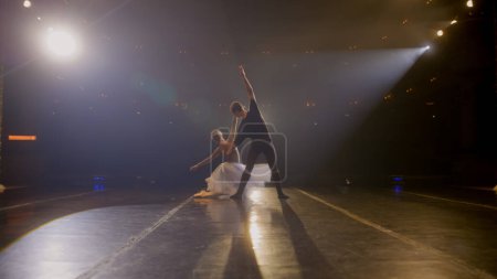 Téléchargez les photos : Les danseurs de ballet pratiquent des mouvements de ballet et répètent la chorégraphie sur une scène de théâtre classique éclairée par des projecteurs. Homme et femme préparent des spectacles de danse théâtrale. Art de la danse classique. - en image libre de droit