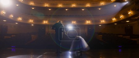 Photo for Ballet dancers bow at the end of choreography rehearsal on classic theater stage illuminated by spotlight. Dance partners prepare for theatrical dance performance. Art of classical ballet dance. - Royalty Free Image