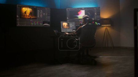 Female editor works in studio on computer using color grading control panel and professional video editing software. Color correction for film post production. Big screens with RGB graphic and levels.