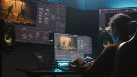 Photo for Female colorist uses color grading control panel, edits video, makes film color correction on computer in studio. Movie footage and RGB wheels on monitor. Big screens and tablet with program interface - Royalty Free Image