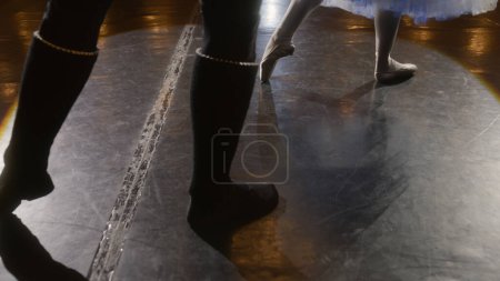 Téléchargez les photos : Gros plan des jambes des danseurs de ballet pratiquant pendant la répétition chorégraphique. Homme et femme se préparent pour la performance, la danse sur scène de théâtre éclairée par des projecteurs. Ballet classique danse art. - en image libre de droit