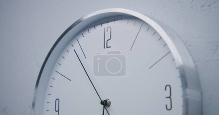 Photo for Static shot of white watch with metal frame hanging on the wall and showing time. Walking wall clock in office with modern design. Strict clock with fast running time pointer. Close up. - Royalty Free Image