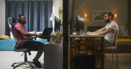 Zwei unterschiedliche Nachbarn sitzen am Computer. Ein Mann fängt an, aus der Ferne zu arbeiten, ein anderer Mann mit Kopfhörern spielt Online-Videospiele. Zwei Wohnungen durch eine Mauer getrennt. Konzept von Nachbarschaft und Lebensstil.