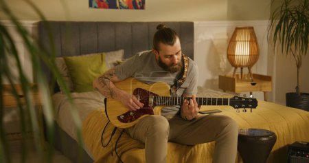 Photo for Man plays guitar in bedroom. - Royalty Free Image