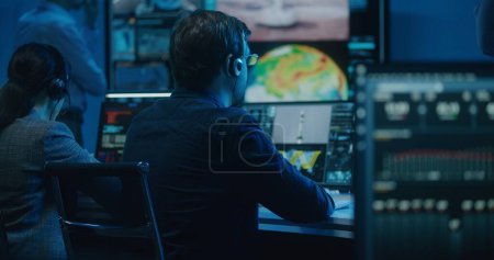 Photo for Diverse flight control operators in headsets monitor space mission on computers in mission control center. Team clap hands after successful space rocket launch displayed on big digital screens. - Royalty Free Image