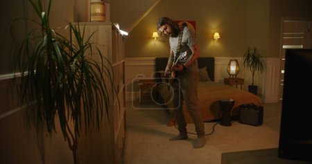Photo for Man plays guitar in bedroom. - Royalty Free Image
