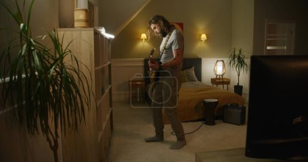 Foto de Hombre toca la guitarra en el dormitorio. - Imagen libre de derechos