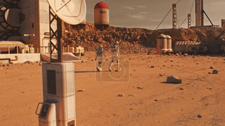 Foto de Dos astronautas, científicos en trajes espaciales caminan sobre la superficie de Marte. Estación de investigación, colonia o base científica en el planeta rojo. Explorando la misión espacial. Concepto de colonización y exploración futurista. - Imagen libre de derechos