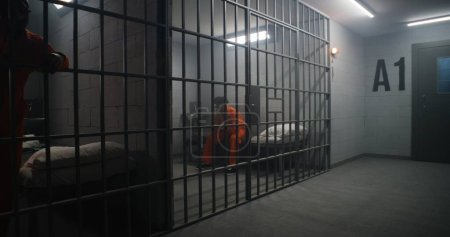 Reclusos afroamericanos en centros de detención o correccionales. Hombre deprimido en uniforme naranja se sienta en la cama de la prisión y mira a la ventana cerrada. Presos cumplen pena de prisión en celda.