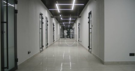 Photo for Doctors, healthcare professionals and patients walk along the bright clinic corridor. Medical staff and people in private hospital or modern medical center. Laboratory or emergency station. Back view. - Royalty Free Image