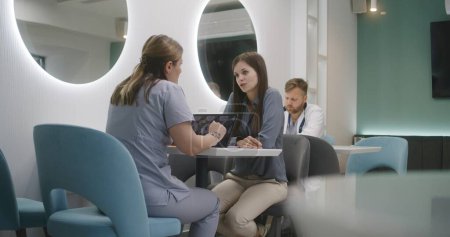 Photo for Female doctor sits in clinic cafe with patient. Professional medic discuss medical diagnostic results with woman. Digital tablet with MRI or CT brain scan image. Hospital or medical center cafeteria. - Royalty Free Image