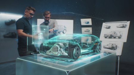 Téléchargez les photos : Deux ingénieurs automobiles professionnels choisissent la carrosserie d'une nouvelle voiture électrique écologique en utilisant un hologramme futuriste de réalité augmentée. Graphismes informatiques 3D du véhicule de haute technologie en développement. Animation VFX. - en image libre de droit