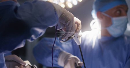 El cirujano varón adulto mira al monitor y opera al paciente con sus colegas. Los médicos profesionales utilizan modernos instrumentos de laparoscopia durante la cirugía en quirófano. Personal médico en el trabajo en clínica.