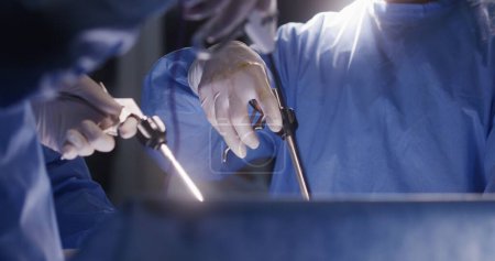 Primer plano de los médicos usando instrumentos de laparoscopia durante la cirugía. Cirujanos profesionales en trajes quirúrgicos realizan operaciones difíciles utilizando equipos modernos. Personal médico salvar la vida en el centro médico.