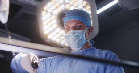 Photo for Face close up of surgeon in lab coat preparing to heart transplant surgery. Doctors, nurses and paramedics perform surgical operating with seriously injured patient. Medical staff in modern clinic. - Royalty Free Image