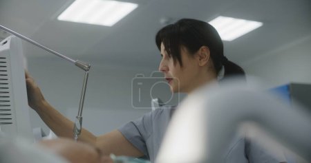 Photo for Friendly nurse talks and takes care of patient, uses hospital monitor. Female doctor checks patient condition after surgery. Emergency room in clinic. Intensive care department in medical facility. - Royalty Free Image