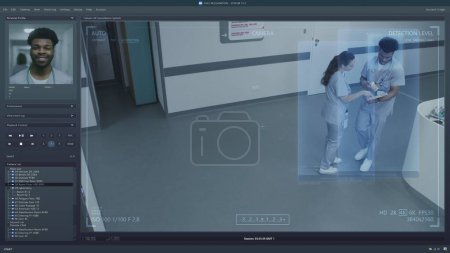 Foto de Reproducción de cámaras de CCTV en la clínica moderna en la pantalla del PC. Interfaz de usuario del programa del sistema de vigilancia y reconocimiento facial de IA. Imágenes de cámaras de seguridad. Personal médico y pacientes en el pasillo del hospital. - Imagen libre de derechos