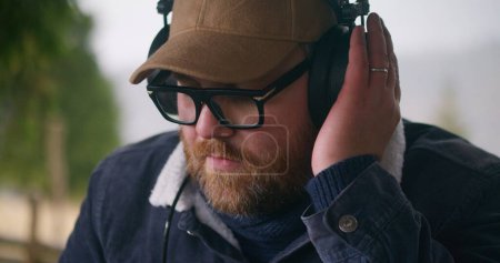 Photo for Close up of Caucasian man wearing headphones playing on digital musical instrument outdoors. Professional musician records music or mixes songs, moves rhythmically. Music creating and mastering. - Royalty Free Image