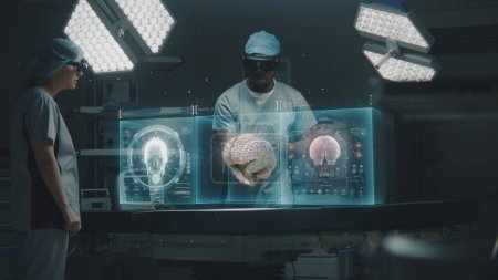 Photo for Diverse surgeons in AR headsets work in operating room. African American specialist uses AI virtual holographic display. 3D graphics of health monitors and human brain. Modern medical facilities. - Royalty Free Image