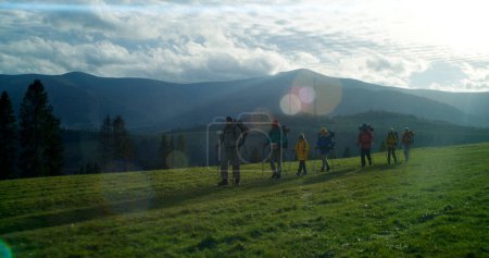 Foto de Foto completa de diversos grupos de turistas con bastones de trekking y mochilas que van en camino a su camping. Compañeros de senderismo durante el viaje o caminata a las montañas de vacaciones en otoño. recreación al aire libre - Imagen libre de derechos