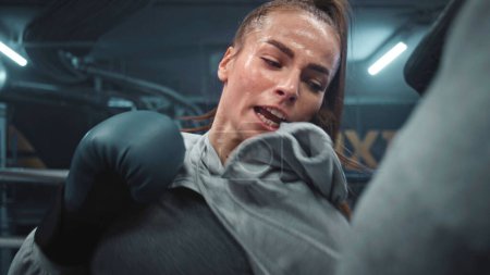 Photo for Close up of female boxer hitting punching mitts while training on boxing ring. Woman in boxing gloves exercises with male trainer in gym before fighting match. Physical activity and workout concept. - Royalty Free Image