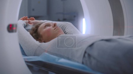 Foto de Primer plano de retrato de una mujer acostada en una tomografía computarizada o PET o resonancia magnética escaneada y moviéndose dentro de la máquina. Escaneando al paciente con tecnologías médicas avanzadas. Laboratorio médico con equipos modernos de alta tecnología. - Imagen libre de derechos