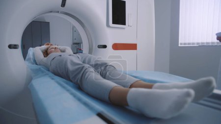 Photo for Close up shot of woman lying on CT or PET or MRI scan bed and moving inside machine. Scanning of patient body and brain using high-tech modern equipment. Medical facility with advanced technologies. - Royalty Free Image